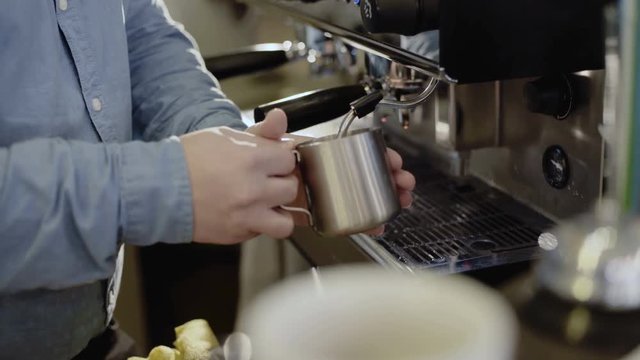 Pouring stream milk into a cup of espresso. 4K