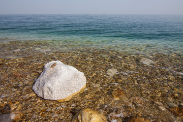 Fototapeta na wymiar Israel - West Bank - Ein Gedi - Waters and stones covered by crystal salt on Dead sea shoreline