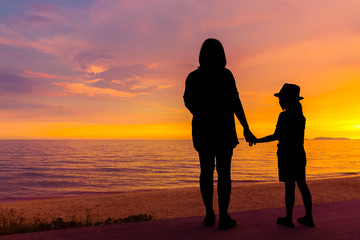 Silhouette mother and daughter on beach with twilight sky in sunset time
