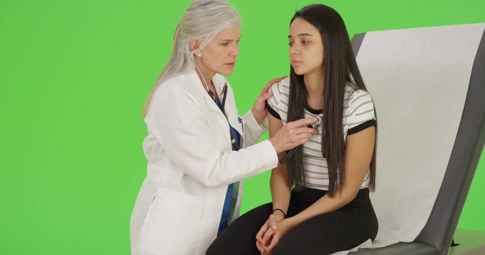A young girl gets an annual check up on green screen. On green screen to be keyed or composited. 