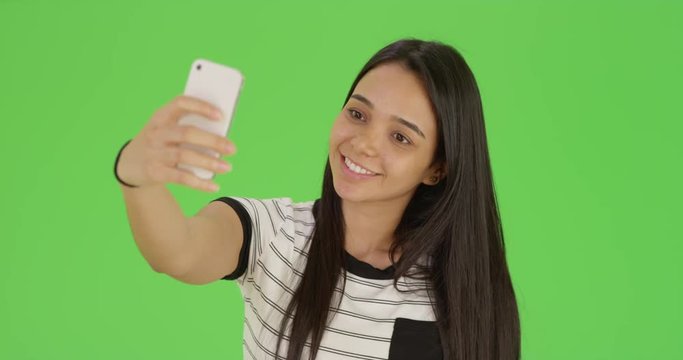 A cute teen takes a selfie on green screen. On green screen to be keyed or composited. 