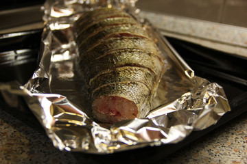 Fresh raw fish in spices in foil on a baking sheet is ready for cooking. Delicious dinner.