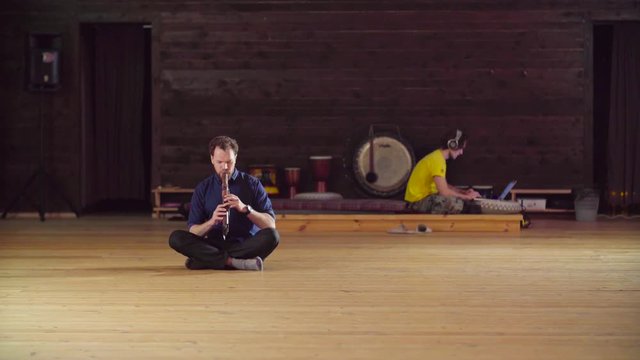 A man sitting on the floor and playing ethnic flute