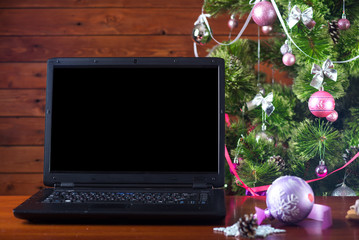 Christmas laptop stands near a Christmas tree, a free space.