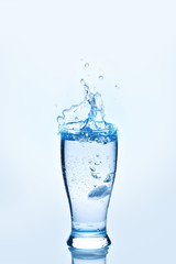 The ice cubes lapping in water glass. Water splashes, Background with copy space.
