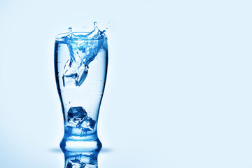 The ice cubes lapping in water glass. Water splashes, Background with copy space.