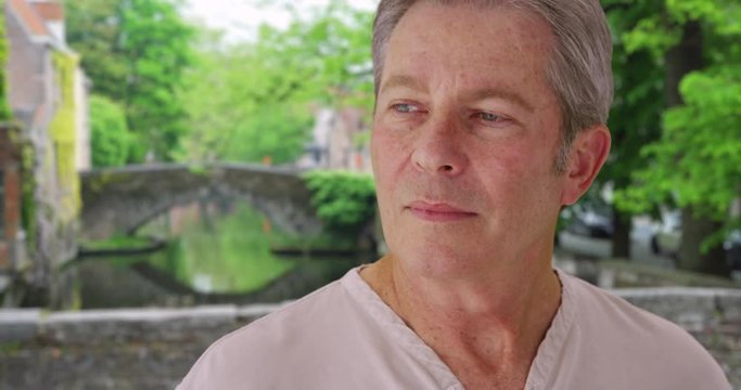 Humorless old white man in Bruges looks around glumly 