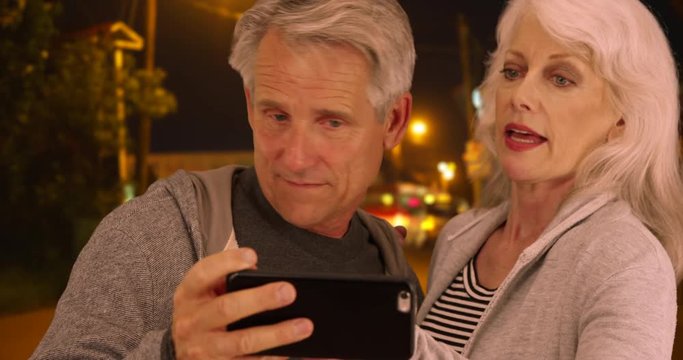 Confused elderly couple lost in a different country and uses smartphone for help