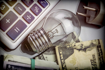 Calculator and money next to a light bulb, the concept of energy saving