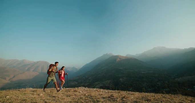 Hiking backpackers on hike in beautiful mountains landscape, trekking smiling happy together. Multiracial couple, young Asian woman and Indian man