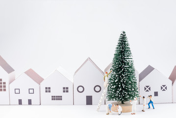 Obraz na płótnie Canvas Miniature tiny people toys enjoy with christmas tree in the paper house town at christmas day isolated on white background with copy space.Theme Christmas day background.