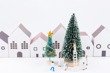 Miniature tiny people toys enjoy with christmas tree in the paper house town at christmas day isolated on white background with copy space.Theme Christmas day background.