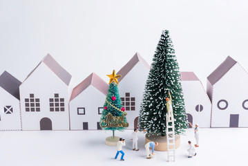 Miniature tiny people toys enjoy with christmas tree in the paper house town at christmas day isolated on white background with copy space.Theme Christmas day background.