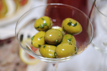 Ripe green olives lie in a cocktail glass. Great background for the menu of a bar or restaurant.