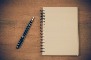 Book note and fountain pen on wood table.