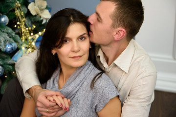 Pregnancy, winter holidays and people concept - happy pregnant wife with husband at home at christmas. Young family celebrating Christmas at home