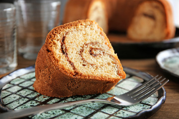 Plate with delicious cinnamon roll cake on table