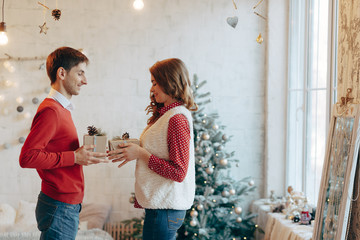 Young couple give Christmas presents to each other