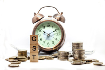 Goods and Services Tax word on Alarm clock and stacks coins on white table, Success in business concept.