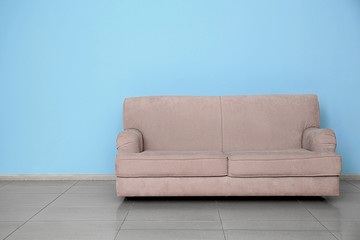 Stylish sofa near color wall indoors