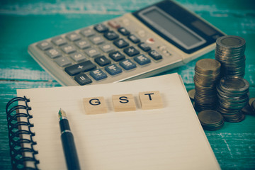 Word of GST on wooden alphabet blocks on book note .Selective focus,shallow depth of field. Finance...