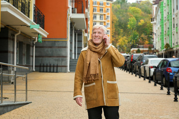 Handsome mature man talking on phone outdoors