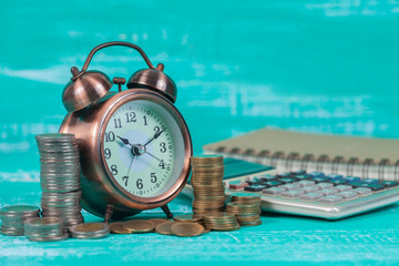 Alarm clock and stacks coins on wood table, Success in business concept.