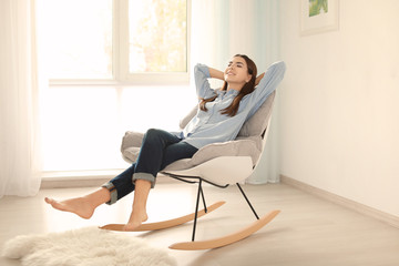 Young woman resting in rocking chair at home