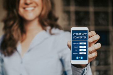 Smiling woman holding a mobile phone with currency converter app in the screen.