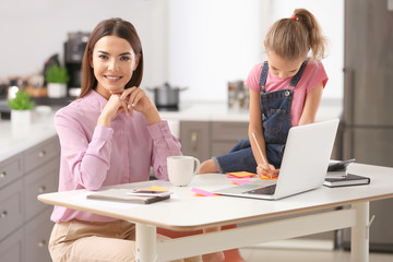 Busy young woman with daughter in home office
