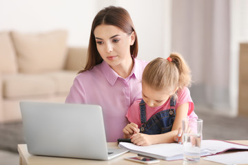 Fototapeta na wymiar Busy young woman with daughter in home office