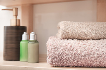 Clean towels and cosmetics on shelf in bathroom