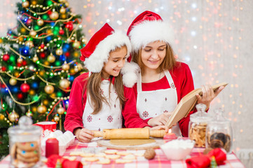 Fototapeta na wymiar Mom and daughter read the recipe while preparing Christmas cookies