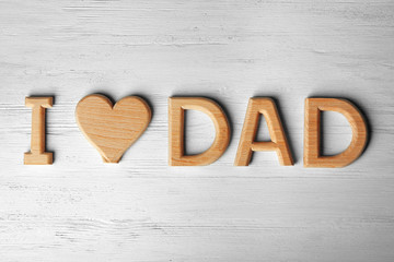 Greeting for Father's day with phrase "I love dad" made of letters on wooden background