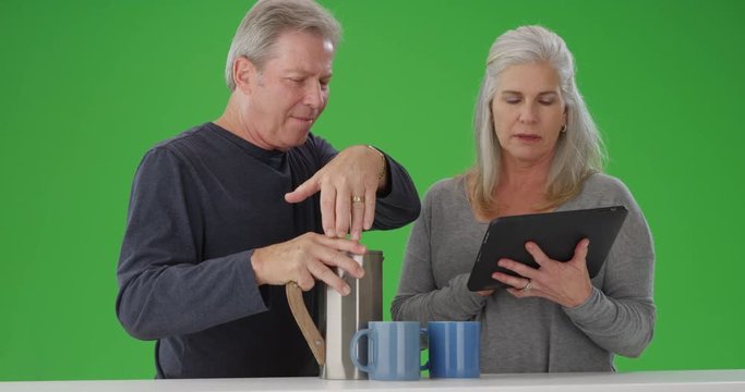 Senior white couple looking at tablet computer during breakfast