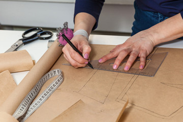 Seamstress is cutting drawing for a dress with scissors. Style and design development and creating garment, clothes sew and repair service, seamstress at work concept