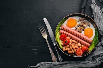English breakfast. Fried eggs, sausages, bacon, beans, toasts, tomatoes, coffee cup on stone table. Top view with space for your text