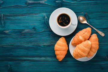 Breakfast, coffee and croissants, on a wooden surface. Top view. Free space for text.