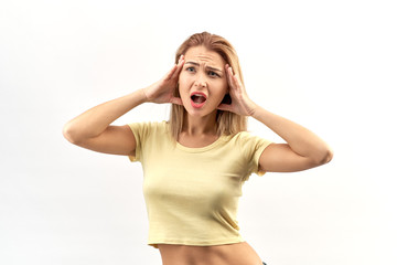 Obraz na płótnie Canvas Young attractive woman posing in Studio isolated portrait, hands on head and mouth wide open. Shocked, stress, horror emotions on her face and a headache