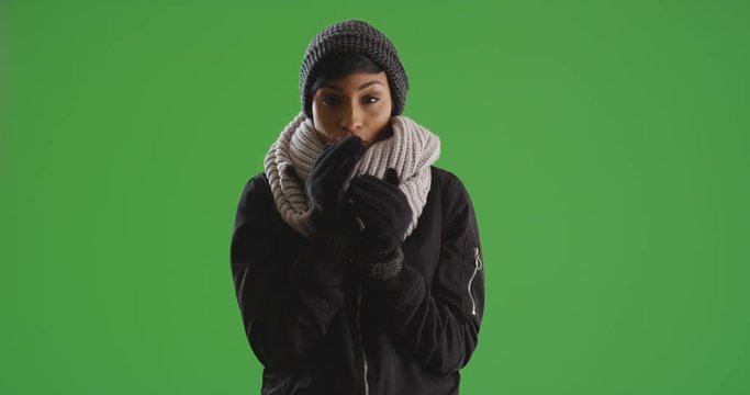 Portrait of African American female wrapped in scarf and gloves, shivering on green screen. On green screen to be keyed or composited. 