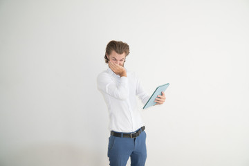 A guy watching something cringy at a tablet on white isolated background.