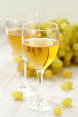 Glass of wine and grapes in the basket on a wooden table.