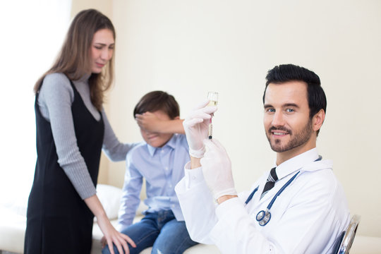 Doctor preparing injection kid at hospital. Kid scary needle when looking doctor hold. People with medical concept.