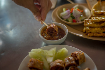Dip the Deep Fried Crab and chicken meat roll (Hoi Jo) in sauce, southern style food of Thailand