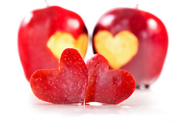 Two red hearts are cut out from apple, two red apples on a background