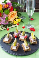 Canapes with rye bread, herring and pickles on a festive table. Valentine's day concept or wedding.