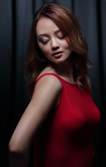 Fototapeta na wymiar Charming brunette in a red dress posing on a black background.