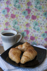 Vertical shot of breakfast with three croissants and large black coffee in an old-fashioned style setup, with copy space and selective focus