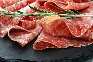 Stone cutting board with sliced salami on it