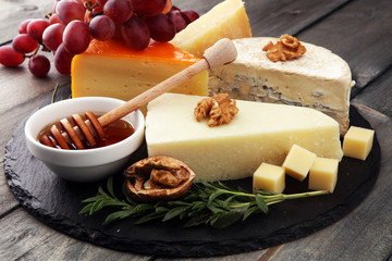 Different types of cheeses on board with walnut and grapes